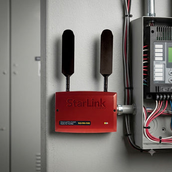 Red fire alarm communicator installed in gray industrial control room