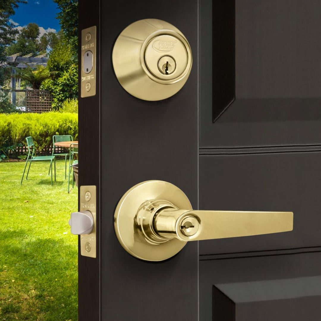 brass entry lock with brass deadbolt on black wood door with backyard chairs behind